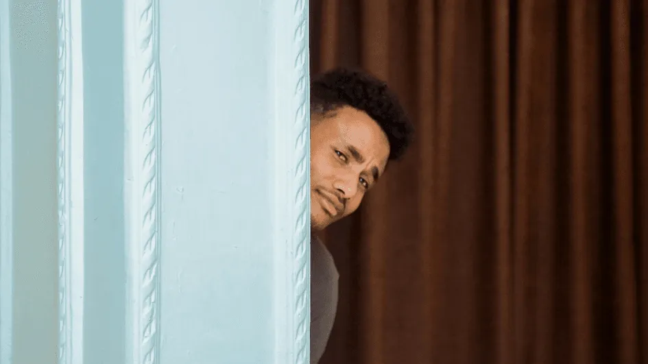 Mann versteckt sich hinter Wand.webp