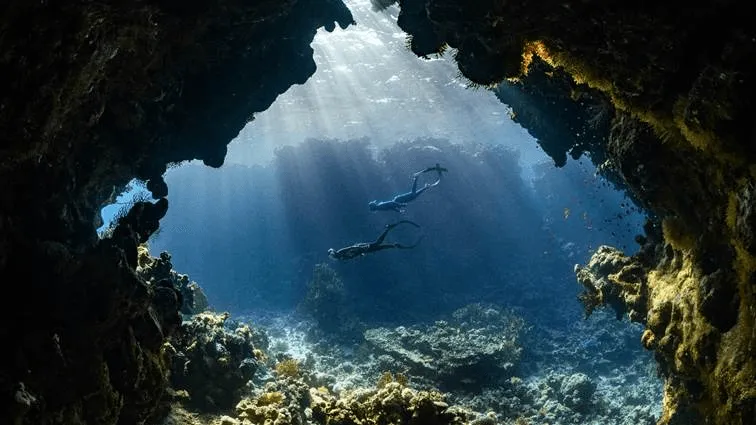 Taucher schwimmen in Höhle.webp